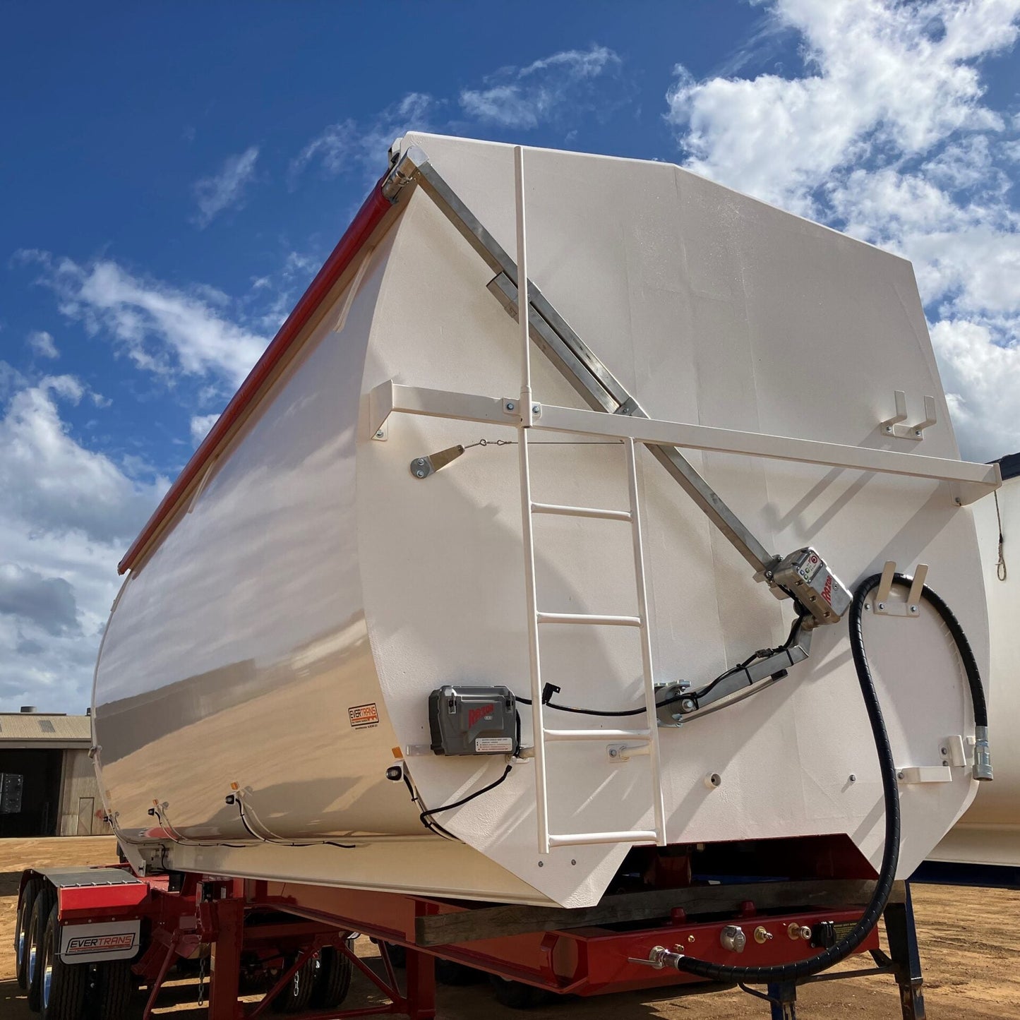 White trailer with a red stripe under a blue sky with clouds